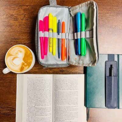 A book, a cup of coffee, a journal, and some highlighters.